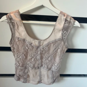 Beige spetslinne - Säljer ett elegant beige spetslinne med vacker blommig design. Linnet är ärmlöst och har en rund halsringning. Perfekt för en stilren look. pris går att diskutera 