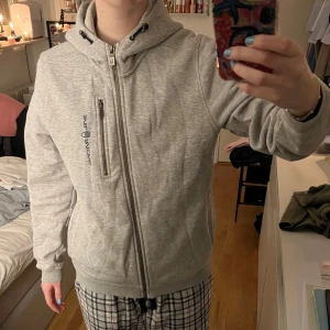 Grå Sail Racing hoodie med zip - Säljer cool hoodie med dragkedja. Storleken är 170 men passar S-M. 