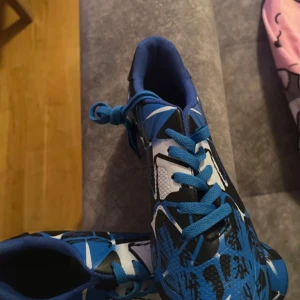 Blå och svarta fotbollsskor - Helt nya snygga blå och svarta fotbollsskor med ett iögonfallande mönster. Skorna har snörning och dobbar för bra grepp på planen. Perfekta för fotbollsträning eller match.