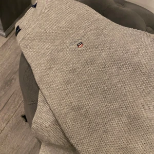 Beige tröja från GANT stl S  - Säljer en stilren beige tröja från GANT i premium bomull. Tröjan har en broderad logotyp på bröstet och en klassisk rund halsringning. Perfekt för en avslappnad och snygg look.