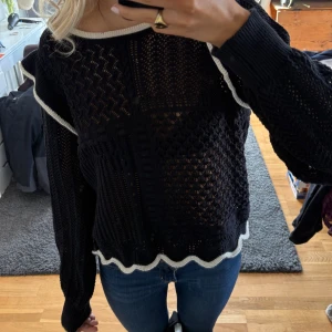 Svart stickad tröja med volangdetaljer - Säljer en svart stickad tröja med volangdetaljer och vita kanter. Använd max 5 gånger
