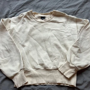 Beige sweatshirt från Weekday - Säljer en stilren beige sweatshirt från Weekday. Tröjan har en rund halsringning och långa ärmar med ribbade muddar vid ärmslut och nederkant. Perfekt för en avslappnad look.