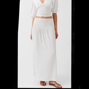 Vit långkjol från Gina - Supersnygg vit långkjol med bred midja från Gina. Slutsåld överallt. Knappt använd. Strl. S-M