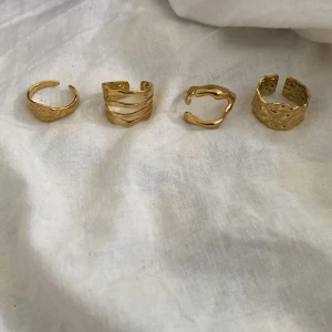 Fyra chunky guldringar i olika former - Säljer ett set med fyra coola guldfärgade ringar i olika chunky designer. En har vågiga linjer, en är organisk och böljande, två har hamrad yta med unik struktur. Perfekt för dig som gillar att mixa och matcha statementringar och vill ha en trendig look.