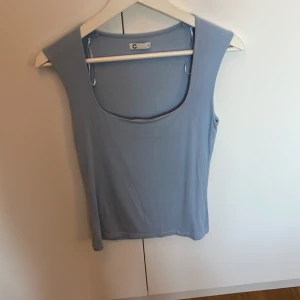 Ljusblå ärmlös linnetopp från Cubus - Säljer en stilren ljusblå linnetopp från C i storlek S. Toppen är ärmlös med breda axelband och har en rundad, djup urringning framtill. Perfekt för varma dagar och enkel att matcha med jeans eller kjol. Bara använd några gånger.