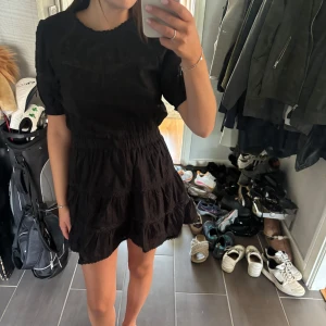 Svart kort klänning från Zara - Supersöt svart klänning från Zara med kort ärm, volangkjol och fina spetsdetalje. ”Saken” man sätter fast knappen med är trasig men går lätt att laga