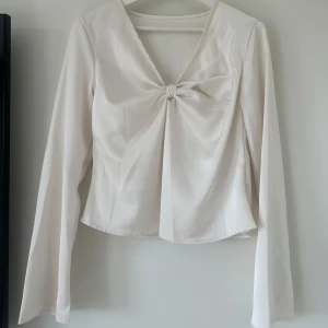 Satintopp med knytdetalj - Fin långärmad topp i satin med en knytdetalj. Lapparna är borta men passar storlek S/M och är bara använd en gång så i mycket gott skick 💕🙌