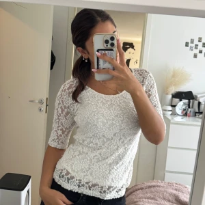 Vit spetsblus med blommigt mönster - Supersöt vit blus i spets med blommigt mönster och trekvartsärmad