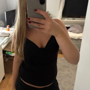 Svart festlig topp - Snygg svart topp med stilren design som passar för olika fest tillfällen. Perfekt för dig som gillar plagg med en modern touch. Toppen har tunna axelband, skriv för bättre bilder. Den är helt oanvänd och köpt på Hm i Italien