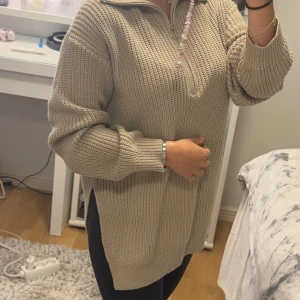 Beige stickad tröja med half zip - Säljer en beige stickad tröja med half zip och krage. Tröjan har en loose passform och långa ärmar, perfekt för att hålla sig varm. Den grovstickade strukturen ger en chill och avslappnad vibe. Passar dig som gillar mysiga och stilrena plagg.