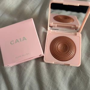 CAIA Glow Blush Hot Toast - CAIA Glow Blush i nyansen Hot Toast, en skimrande rouge i varm kopparbrun ton. Kommer i en söt ljusrosa dosa med spegel och har en snygg cirkelmönstrad yta. Perfekt för att ge kinderna ett glow och extra färg. Helt ny och aldrig använd endast öppnad därför är förpackningen bruten.😊