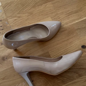 Beige lackade pumps från INOCINI - Snygga beige pumps i lackat skinn från INOCINI. Skorna har spetsig tå och smal klack som ger en elegant look. Så snygga!