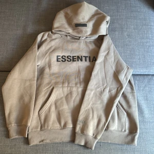 Beige Essentials Fear of God hoodie - Säljer en beige brun hoodie från Essentials Fear of God i storlek S. Tröjan är rätt loose och sitter lite löst på grund av modell. Skriv gärna om ni har frågor. ÄR öppen för förhandlingar och bud:)
