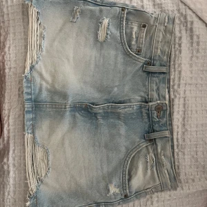 Ljusblå jeanskjol med slitningar - Säljer en ljusblå kort jeanskjol från Pull & ber med coola slitningar och en fin ljusblå tvätt.