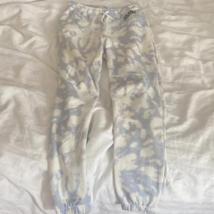 Blåvita mjukisbyxor H&M  - Säljer ett par mjukisbyxor från H&M i blåvitt batikmönster med trycket 'Dreamer Forever' på höften. Byxorna har resår och snörning i midjan samt resår vid bensluten. Perfekta för chill dagar eller när du vill vara extra comfy.