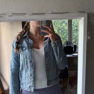 Ljusblå jeansjacka från Zara - Säljer en klassisk ljusblå jeansjacka från Zara med snygga bröstfickor och knappar framtill. Jackan har en rak passform och är tillverkad i denim med coola sömdetaljer. Perfekt att ha nu på sensommar och till hösten.