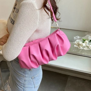 Rosa axelväska med veckad design - Snygg rosa axelväska med veckad och puffig design. Väskan har ett kort axelband och stängs med dragkedja. Materialet är mjukt syntet som ger en cool och modern look. Perfekt storlek för det viktigaste och ger en poppig färg till din outfit.