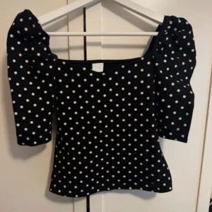 Svart prickig blus med puffärm - Supersöt svart blus med vita prickar och puffiga korta ärmar. Den är i storlek XS men jag har S och den passa jätte bra🥰