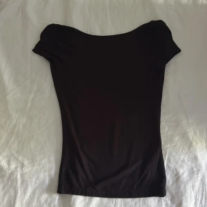 Svart topp med öppen rygg Gina Tricot - Säljer en svart, tight topp från Gina Tricot i storlek XS. Toppen har korta ärmar och en djup, öppen rygg som ger en snygg och stilren look. Tillverkad i mjuk bomullsmix som sitter skönt mot kroppen. 