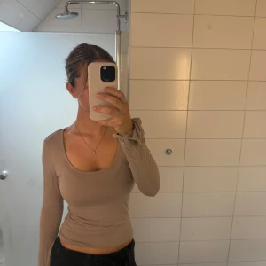 U-ringad tröja  - Säljer en rosa/beige u-ringad tröja från Ginatricot med slits i ärmarna. Tröjan är i storlek M och är nyköpt för 200kr.