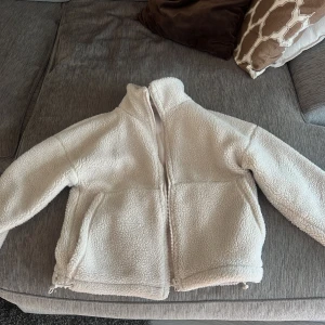 Vit teddyjacka från Carin Wester XS - Mysig och fluffig teddyjacka i vitt från Carin Wester, modell Juna. Jackan har dragkedja framtill, hög krage och två stora fickor. Tillverkad i 100% polyester och har en loose fit som ger en chill vibe. Perfekt för kyliga dagar när du vill vara både varm och snygg. Nypris 700.