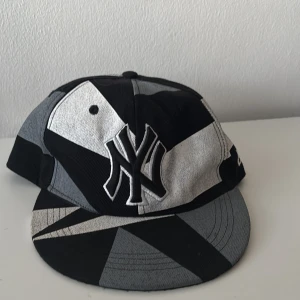New Era New York Yankees keps 59FIFTY - Snygg New York Yankees keps från New Era 59FIFTY med coolt geometriskt mönster i svart, grått och vitt. Broderad NY-logga fram och bak, samt New Era-logga på sidan. Passformen är normal och materialet är bomull. Perfekt för dig som vill sticka ut med din stil.