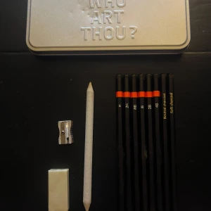 Who Art Thou? - Ett stilrent ritset i metallask med texten 'Who Art Thou?'. Innehåller blyertspennor i olika hårdheter, kolpennor, sudd, pennvässare och stompf. Perfekt för dig som vill utforska din kreativa sida och skapa konstverk var du än är.