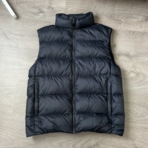 Väst   - Svart light weight dunväst med hög krage och quiltad design . Västen har dragkedja framtill och två sidofickor. Perfekt för lager-på-lager och enkel att matcha med hoodies eller tröjor. Två små fläckar på insidan som knappt syns (sista bilden)