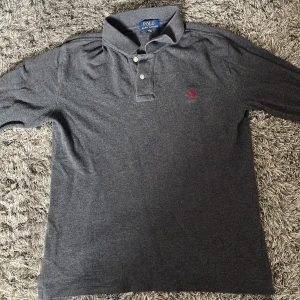Grå långärmad pikétröja Polo Ralph Lauren🤩✅ - Mörkgrå långärmad pikétröja från Polo Ralph. Passar dom runt 170cm och hör av dig vid frågor 🤩🙌
