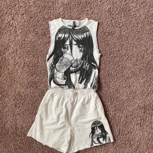 Billie Eilish x H&M vit set anime - Unikt vitt set från Billie Eilish x H&M med anime-inspirerat tryck i svart och lila på både linne och shorts. Mjukt bomullsmaterial med elastisk midja och lila sömmar. Perfekt för dig som gillar streetstyle och coola prints. Är i storlek XXS och är nästan helt oanvänd.
