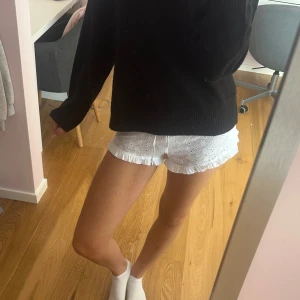 Vita shorts med spets och volang - Säljer ett par vita shorts med broderade blommor, spetsdetaljer och volangkant. De har snörning i midjan och är gjorda i mjuk bomull. Perfekta för sommaren eftersom de är super sköna och söta!!💕💕
