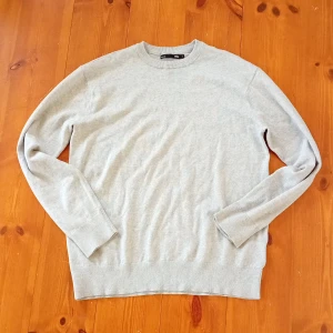 Grå tröja från 157 - Säljer en stilren grå tröja från 157 i storlek S. Tröjan har en klassisk rund hals och långa ärmar med ribbade muddar. Perfekt för en avslappnad look.