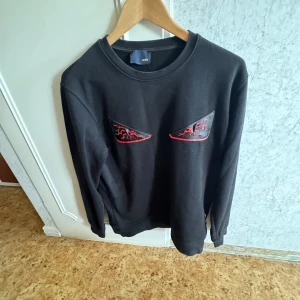 Svart tröja från Fendi med röda detaljer - Säljer en svart tröja från Fendi med unika röda detaljer som liknar ögon på framsidan. Tröjan har en klassisk rund hals och långa ärmar. Perfekt för dig som vill ha något stilrent men med en twist. 🖤