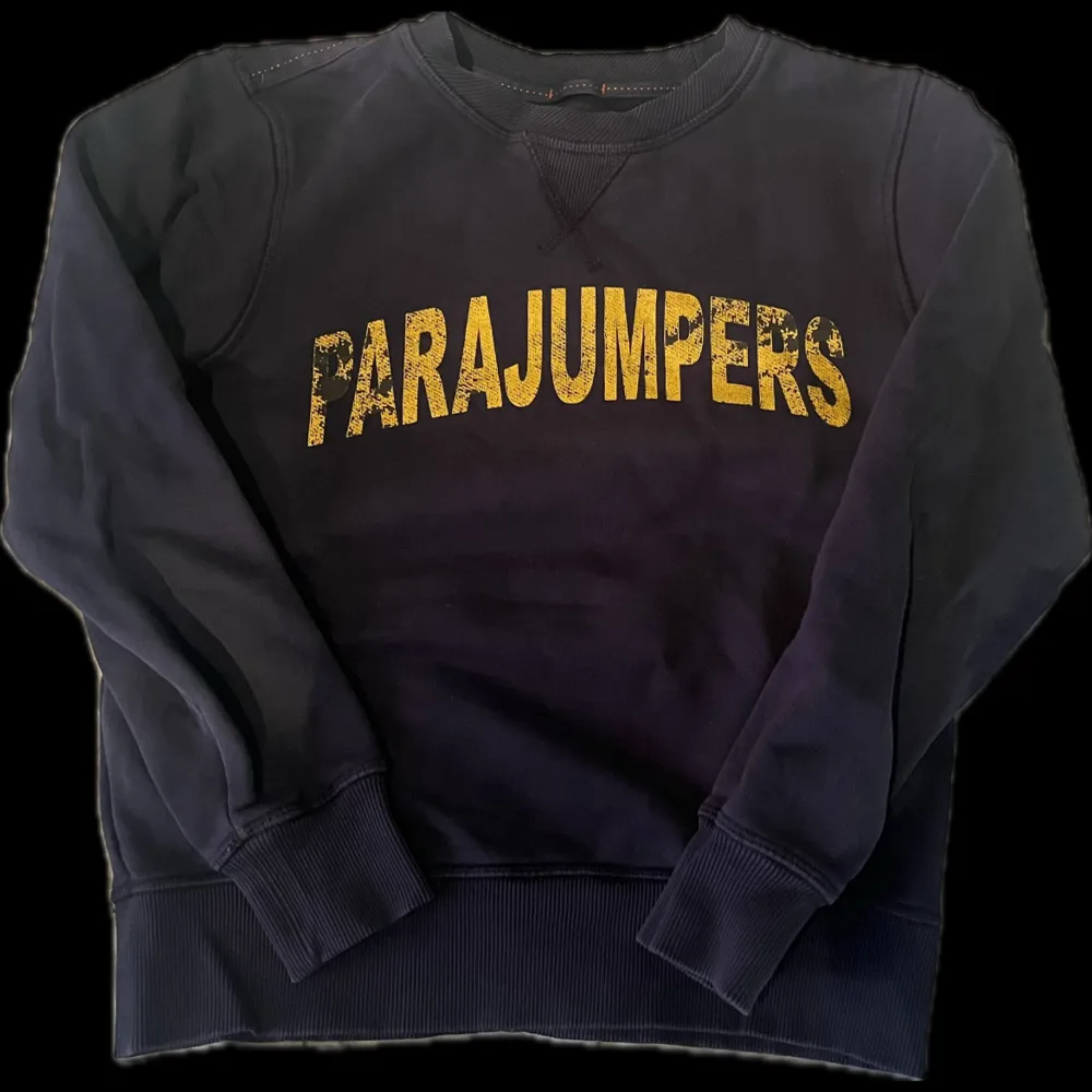 Säljer en svart sweatshirt från Parajumpers med stort gult tryck på framsidan. . Neuletakit & Villapaidat.