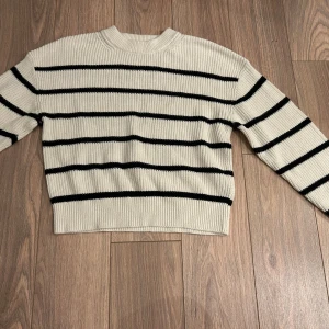 Vit och svart randig tröja från H&M - Säljer en stilren vit tröja med svarta ränder från H&M. Tröjan är stickad och har en normal passform med långa ärmar. Perfekt för en avslappnad look. Jätte skön!!!