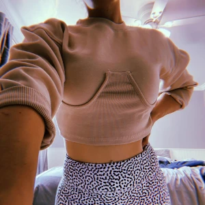 Beige croppad tröja från Missguided - Säljer en beige croppad tröja från Missguided med unik design framtill. Tröjan har långa ärmar och ribbade kanter. Perfekt för en trendig look!