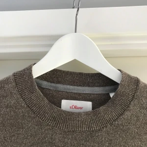 Brun stickad tröja från s.Oliver - Säljer en stilren brun stickad tröja från s.Oliver. Tröjan har en klassisk rund halsringning och långa ärmar. Perfekt för kyligare dagar och enkel att matcha med olika outfits.