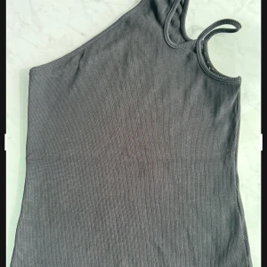 Svart topp  - Snygg svart topp från NLY Trend i ribbat material. Perfekt för en stilren look med en unik asymmetrisk design. Passar bra till både jeans och kjol för en snygg outfit.  Säljer på grund av att jag har flera liknande toppar.  Priset kan diskuteras 