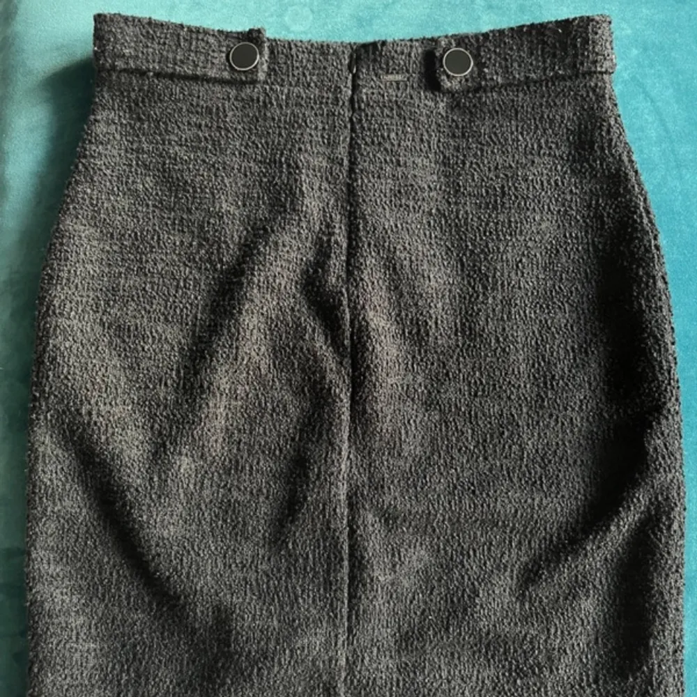 Snygg grå kjol från Guess med en stilren design. Kjolen har en slits framtill och dekorativa knappar i midjan. Perfekt för en chic look!. Hameet.