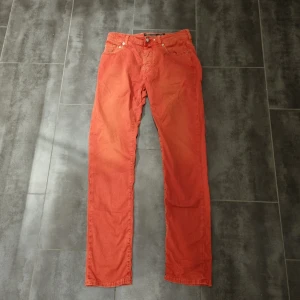 Röd byxor från Jacob Cohen - Snygga röda byxor från Jacob Cohen i storlek 33. Byxorna har en klassisk design med fem fickor och knappgylf. Perfekta för en snygg outfit 