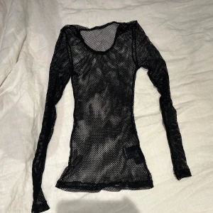 Svart fishnet tröja köpt på blue fox - Säljer en svart fishnet nättröja från blue fox märke Burleska. Tröjan har en tight passform och är långärmad