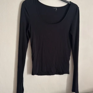 Svart långärmad topp - Säljer en stilren svart långärmad topp med rund halsringning. Perfekt för lager-på-lager eller som den är. Passar till många olika outfits!