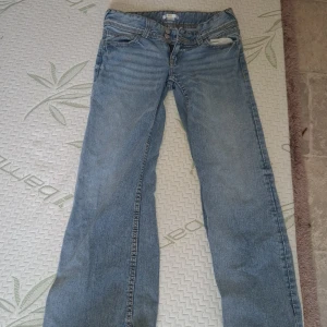 Blå jeans från Gina Tricot - Säljer ett par klassiska blå jeans från Gina Tricot. De har en normal passform med en lätt slitning vid fickan och traditionella fem fickor. Perfekta för en avslappnad stil.