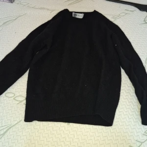 Svart tröja från Gilli - Säljer en klassisk svart tröja från Gilli. Tröjan har en enkel design med långa ärmar och ribbstickade muddar vid ärmslut och nederkant. Perfekt för en stilren look.