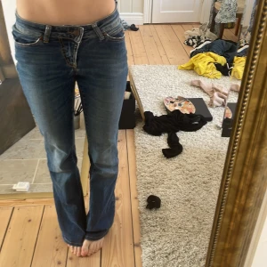 Blå bootcut jeans - Snygga blå bootcut jeans med låg midja. Perfekta för en avslappnad stil. Klassisk femficksdesign och dragkedja framtill. Ihopsydd vid fickorna med vita snygga broderier.