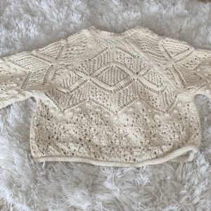 Beige stickad tröja från Zara - Säljer en mysig beige stickad tröja från Zara med ett vackert hålmönster. Tröjan har en normal passform och långa ärmar, perfekt för kyliga dagar. Den är både stilren och bekväm, ett måste i garderoben! 💫 Endast andvänd 4 ggr