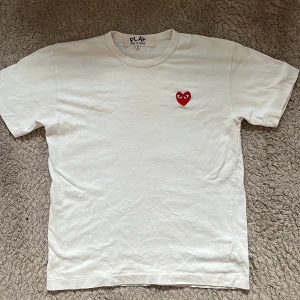 Play comme des garcons t shirt - Skick: Helt okej ( den har några fläckar som syns om man håller tröjan mot en lampa, men dom syns knappt när man har den på sig ) Det är även tre små hål som man kan se på sista bilden. Den är mer S än M.