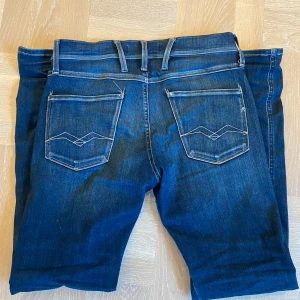 Replay Anbass Slim Jeans - Snygga blå jeans från Replay med klassisk femficksdesign och stilrena sömmar på bakfickorna. Perfekta för en avslappnad look. Riktigt feta jeans med fet tvätt som är sparsamt använda, slim passform i storlek 29/32! Vid funderingar eller frågor är det bara att höra av sig!😊🤝 // Leon