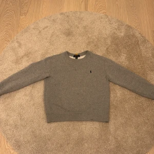 Ralph Lauren sweatshirt grå - Säljer en stilren grå tröja från Ralph Lauren. Tröjan har en klassisk design med rund hals och långa ärmar. Perfekt för en avslappnad och snygg look.