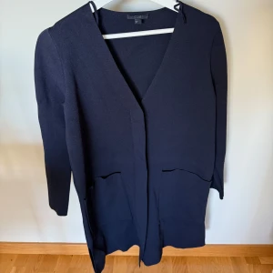 Mörkblå cardigan jacka från COS - 🫧En gång använd mörkblå COS-kofta med lång ärm, v-ringning och fickor fram.  🫧Koftan har dolda knappar och sprund nedtill. 🫧Storlek Xs. 🫧Som ny. Tvättad. 🫧Ordinarie pris över 1000 kr. 🚭Djurfritt och rökfritt hem.